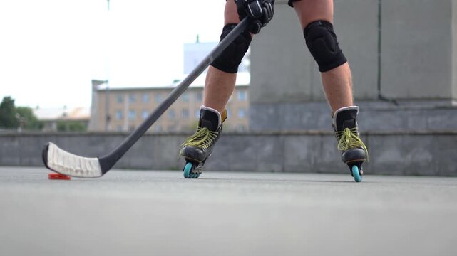 Close-up of a middle-aged man's legs practicing roller skating techniques on a sunny asphalt rink, showcasing his dedication and skill in this dynamic sport. Slow motion 4k footage.