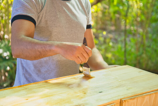 una persona con una brocha de pintura barnizando una madera