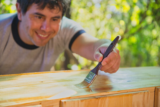 hombre sonriente con una brocha pintando una madera
