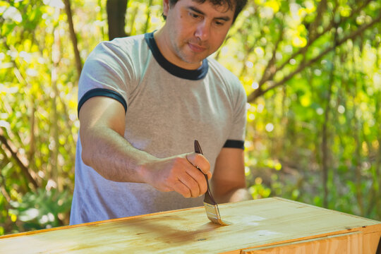 Hombre joven pintando un mueble en el jard&iacute;n