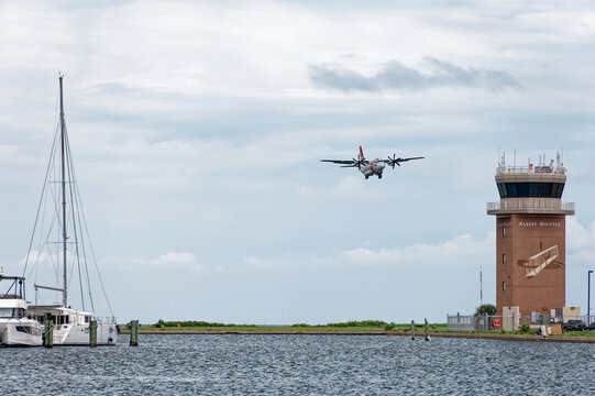 Coast Guard Turboprop aircraft approaches a harbor runway beside a brick control tower Albert Whitted Airport and moored yachts. Editorial Use Only July 29, 2026 St. Petersburg,FL USA. With rippling w
