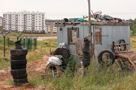  Illegal garbage dump of old furniture on a green hill near a dirt road, with new residential buildings in the background. Concept of environment pollution, illegal waste dumping and social issues now
