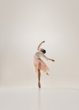 Graceful ballerina curving body in lyrical pose while balancing en pointe. Concept of body awareness, poetic choreography, elegant wellness marketing.