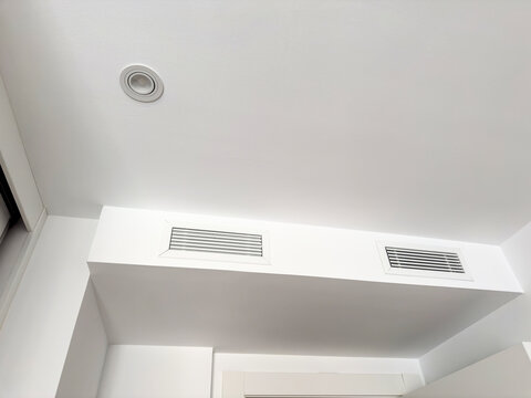A white ceiling bulkhead with two linear air diffusers and a recessed downlight. Concealed HVAC ventilation and lighting