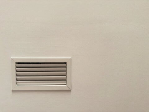 A rectangular grille with horizontal louvers of an air conditioning system in a ceiling bulkhead. Concealed HVAC distribution