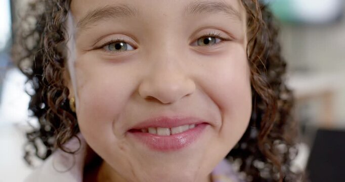 Preteen girl responding to off-camera cue, smiling, revealing teeth and gold hoop at home