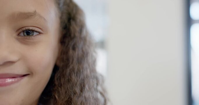 Preteen girl reacting to camera, smiling wider holding gaze by window showing tooth gap, copy space