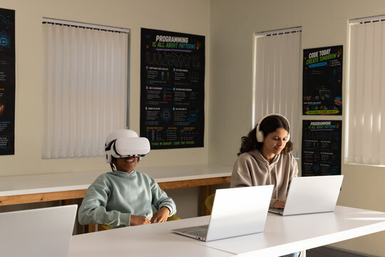 African American students in computer lab, male wearing VR headset, female typing on silver laptop
