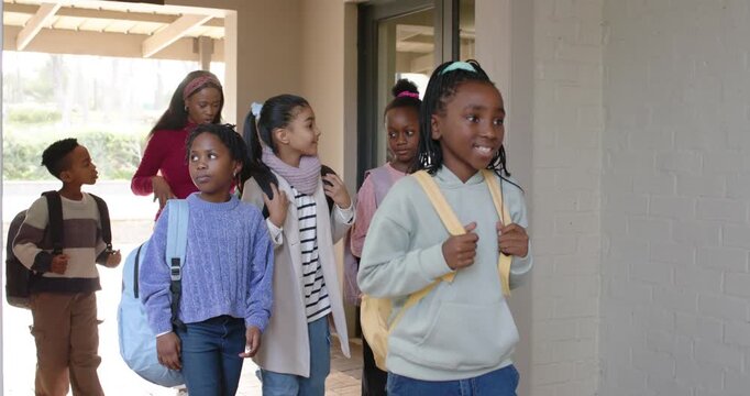 African American kids arriving at school, walking on brick porch, adjusting backpacks to enter