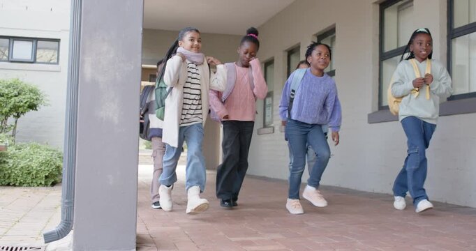 African teenage students entering school walkway from door walking adjusting bags heading to class