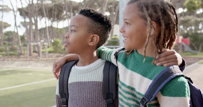 African American preteen boys reacting to soccer game on turf, talking and smiling with backpacks