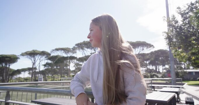 Teen girl leaning rail at park camera moving causing turning to lens smiling laughing copy space