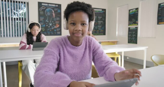 African American teen in purple sweater starting lesson, tapping tablet in class, laughing