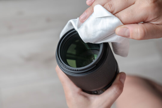 Person cleaning camera lens using microfiber cloth