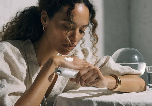 Introspective Moment: Woman Applying Cream On Hands