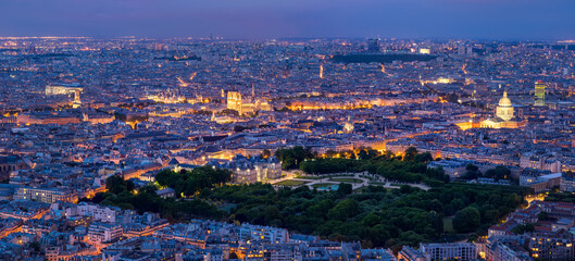 Fototapeta premium Panoramic elevated view of the illuminated Paris skyline at twilight featuring Notre-Dame de Paris Cathedral, the Pantheon and the Luxembourg Gardens, France