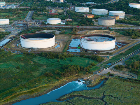 Aerial view of the Fawley Refinery featuring large storage tanks, industrial infrastructure, and coastal marshland in Southampton, England, United Kingdom.