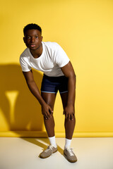 Naklejka premium Handsome African American man showcasing stylish summer fashion against a vibrant yellow backdrop