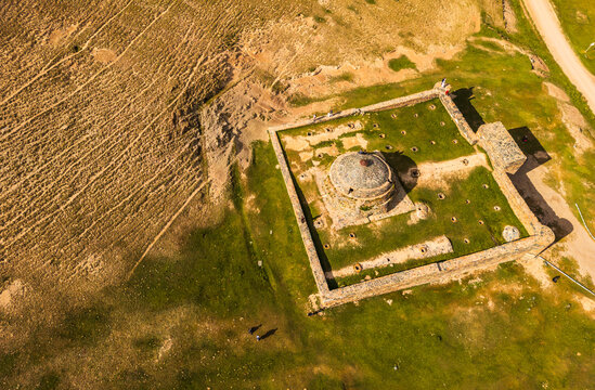Aerial view of Tash Rabat Caravan Palace, an ancient stone caravanserai set within the vast, grassy landscape of the mountains, At-Bashi District, Naryn Region, Kyrgyzstan.