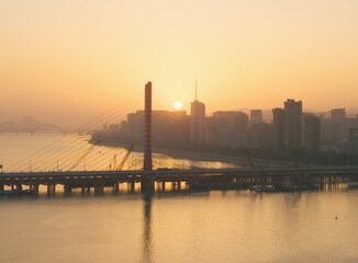 Fototapeta premium Aerial view of Hangzhou Qiantang river bridge at golden hour sunset with city skyline