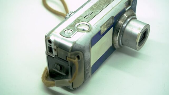 Rotating display of an old vintage digital camera on a clean white background, capturing retro tech trends, nostalgic photography equipment, and commercial product motion concepts.