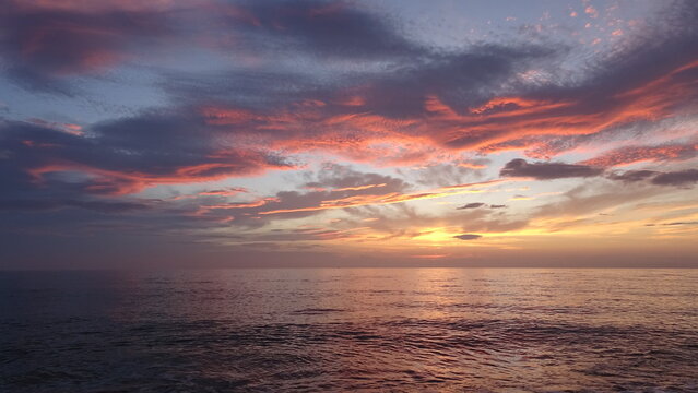 Dramatic Red and Blue Cloud Formations Over the Sea at Sunrise.
A 4k photograph focusing on striking dramatic cloud formations painted with red, pink, and dark blue colors over the ocean.