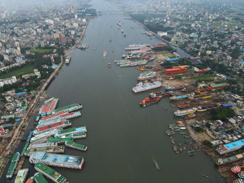 Aerial view of Sadarghat Launch Terminal with numerous passenger launches and cargo vessels docked along the busy Buriganga River in the dense urban cityscape of Dhaka, Dhaka Division, Bangladesh.