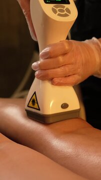 Vacuum roller massage. Lymphatic drainage and RF lifting stage. Dim atmospheric warm light. Masseuse massages a woman's leg with a device. self-care, care, weight loss. slow motion
