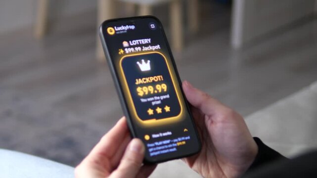 Mobile lottery app displaying a glowing JACKPOT victory screen. User celebrates a 99.99 dollars grand prize win with a crown and stars. 