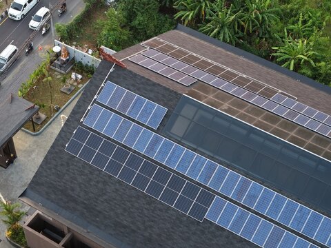 Aerial view of solar panels installed on a dark shingled roof at the PT. Tower Bersama Regional Office Balinusra in Kecamatan Denpasar Selatan, Bali, Indonesia.