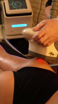 Vacuum roller massage. Anti-cellulite stage. Dim atmospheric warm light. Masseuse massages a woman's leg and thighs with a device. self-care, care, weight loss.