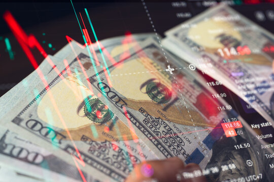 American hundred dollar bills overlaid with stock market candlestick charts and financial graphs