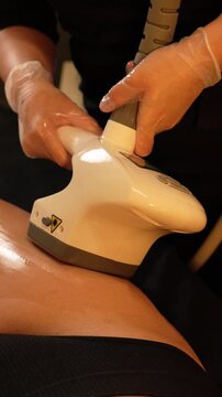 Vacuum roller massage. Lymphatic drainage and RF lifting stage. Dim atmospheric warm light. Masseuse massages a woman's leg with a device. self-care, care, weight loss. slow motion