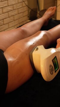 Vacuum roller massage. Lymphatic drainage and RF lifting stage. Dim atmospheric warm light. Masseuse massages a woman's leg with a device. self-care, care, weight loss. slow motion
