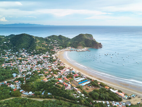 Aerial view of the coastal town of San Juan del Sur with its bay, numerous boats, and surrounding green hills in San Juan del Sur, Rivas, Nicaragua.