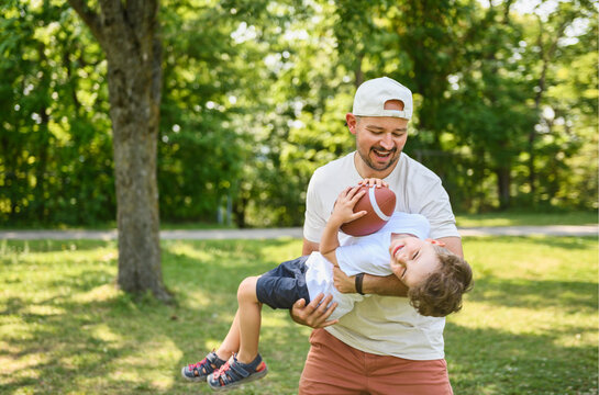 man and young boy playing american football on a court, teaching little player and spending time outdoors