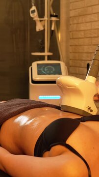 Vacuum roller massage. Lymphatic drainage and RF lifting stage. Dim atmospheric warm light. Masseuse massages a woman's stomach with a device. self-care, care, weight loss. slow motion