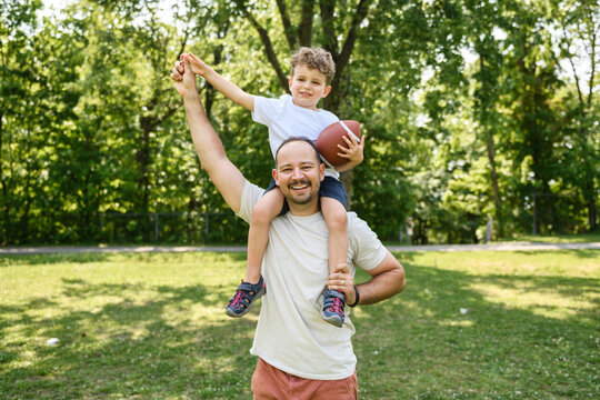 man and young boy playing american football on a court, teaching little player and spending time outdoors