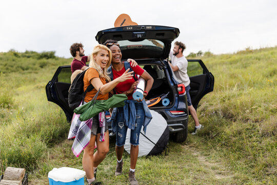 Friends Enjoying a Camping Trip in Nature With a Car Parked on the Side of a Hiking Trail