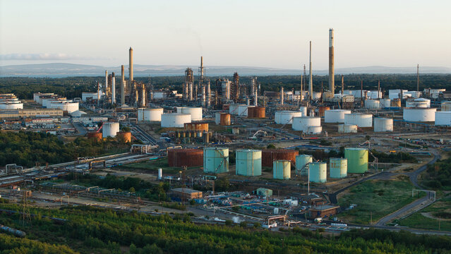 Aerial view of Fawley Refinery featuring large storage tanks, industrial chimneys, and complex processing infrastructure set within a green landscape in Southampton, England, United Kingdom.