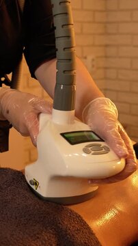 Vacuum roller massage. Anti-cellulite stage. Dim atmospheric warm light. Masseuse massages a woman's stomach with a device. self-care, care, weight loss. slow motion