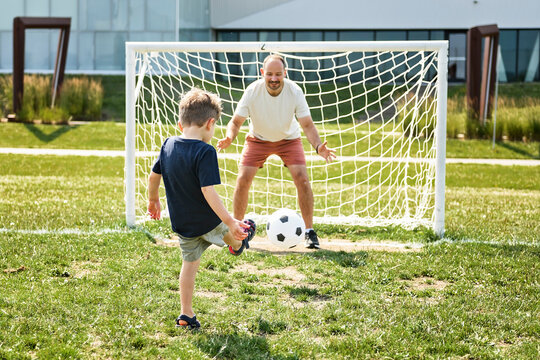 man with child playing football outside on field