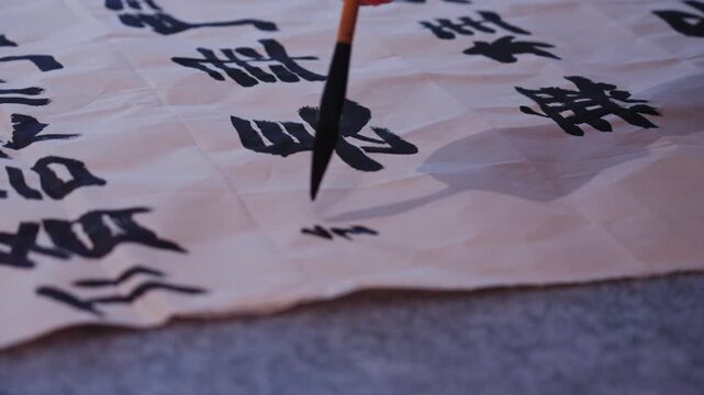 Close up of calligraphy brush writing small Chinese characters on traditional rice paper