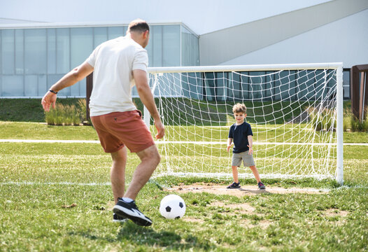 man with child playing football outside on field