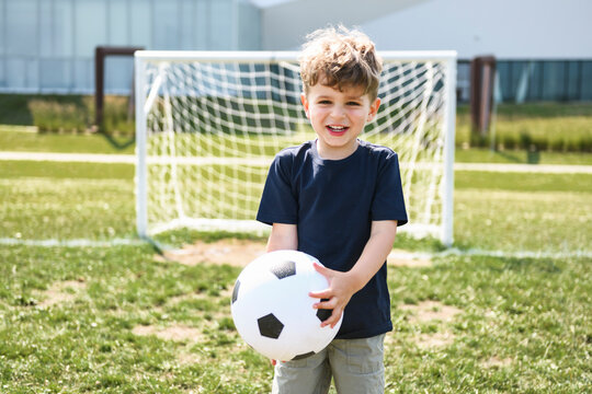 man with child playing football outside on field