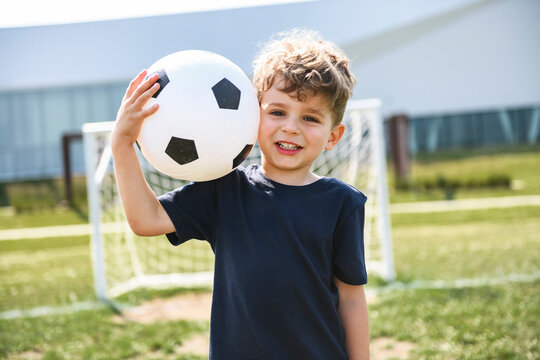man with child playing football outside on field