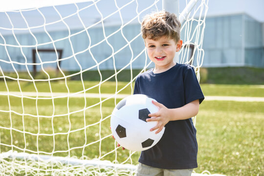 man with child playing football outside on field