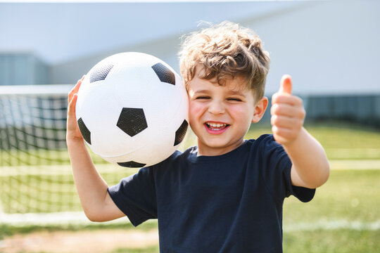 man with child playing football outside on field