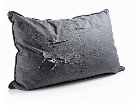 Worn charcoal gray pillow with torn seam and pilled knit fabric isolated on white background