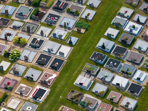 Aerial view of a cemetery with rows of gravestones, stone monuments, and manicured grass paths in a rural setting in Juzintai, Panevezys County, Lithuania.